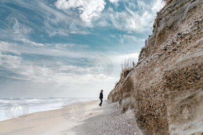 Sandy Cross walking the beach along the face of escarpment erosion.