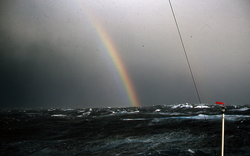 Rainbow over a rough open ocean.