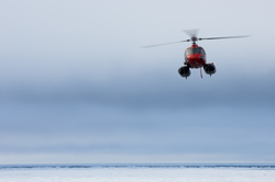 Helicopter in flight over ice.