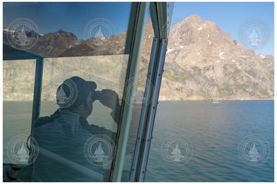John Kemp using binoculars to survey the Greenland shoreline.