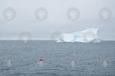 Researchers transit out to a large iceberg to take photos.