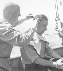 Otto Solberg cutting Captain Adrian Lane's hair  on deck