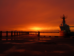 View of sunset looking out off Dyer's dock, featuring Oceanus at WHOI dock.
