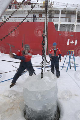 John Kemp attempts to knock ice off a dropline coming out of an ice hole.