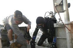 Rocky Geyer and Jay Sisson recover a lost tripod in 15 feet of water.