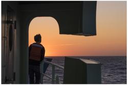 A researcher watching the sunset from R/V Knorr.