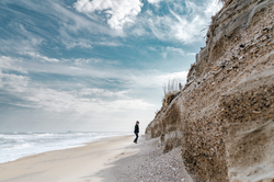 Sandy Cross walking the beach along the face of escarpment erosion.