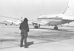 WHOI C54Q aircraft on runway, man in coat standing in view
