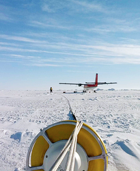 Ice buoy on the ice with the small transit plane in the background.