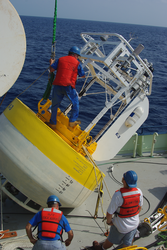 John Kemp on top of a buoy on the deck of Oceanus.