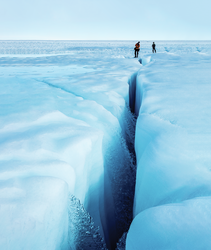 Water flowing into a long icy crevasse in Greenland.