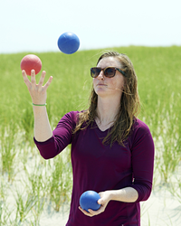 Melissa Mouton juggling three balls at the beach.