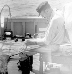 Bill Schevill writing in notebook on deck of Bear