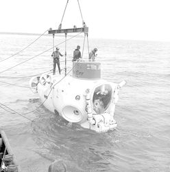 Sea Cliff suspended over the water, three people standing onboard