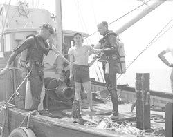 Three men on deck of the Asterias, two divers