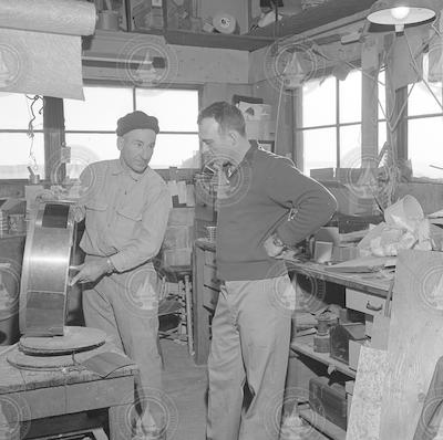 Bill Gallagher and unidentified person in mechanic's shop.