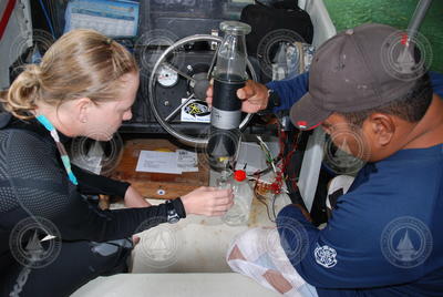 Katie Shamberger and another person collecting a water sample.