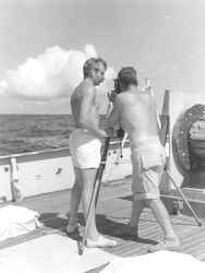 Unidentified men looking at Nansen bottle on deck of Crawford