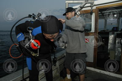 Pat Lohmann assisted by Rocky Geyer prior to his dive to search for a tripod.