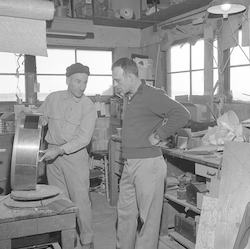 Bill Gallagher and unidentified person in mechanic's shop.