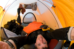 Chris Linder looking up at his camera in his tent.