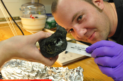 Frieder Klein holding an identifying label for a recovered basalt specimen.