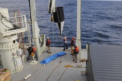 Scientists and crew deploying a sediment net trap.
