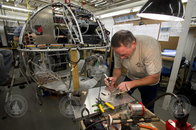 Bob Waters working on electrical systems for the Alvin sphere "bird cage".