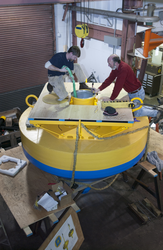 Mike McCarthy and Neil McPhee working on top of buoy in shop.