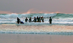 Researchers carrying an instrument tower into the surf.
