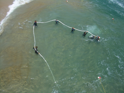 Researchers using high-pressure hose to fluidize sand on the seafloor.
