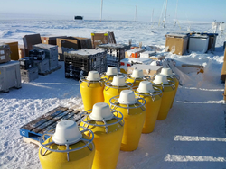 Yellow ice buoys and other equipment in a staging area for plane loading.