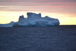 Sunset behind an Antarctic iceberg.