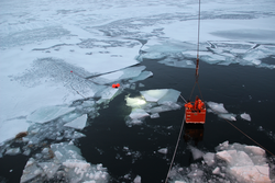 Lights of the hybrid remotely operated vehicle NUI shine beneath an ice floe.
