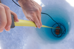 Mark Behn dropping seismometer instrumentation down an ice hole.