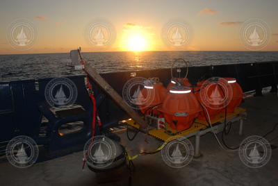 Ocean bottom seismometer on deck in front of sunset.