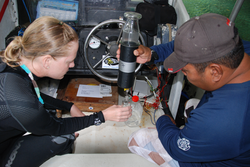 Katie Shamberger and another person collecting a water sample.