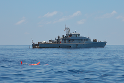 Spray Glider operating on surface in foreground off Seychelles Islands.