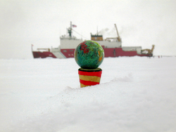 Glass blown orb placed in snow with Healy in background.
